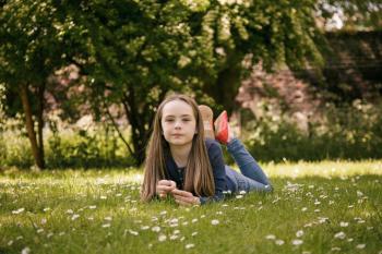 Young pre teen girl lying on grass in park