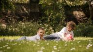 Brothers laying on grass with football
