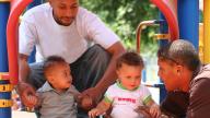 Black fathers with children playing in a playground