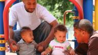 Two black dads with two young boys on play structure