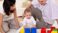 Baby playing with building blocks with couple