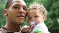 Young black man holding baby up close outdoors