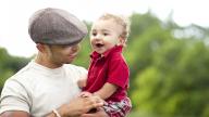 man in cap holding baby son