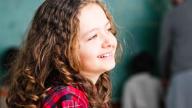 young girl curly hair smiling in classroom